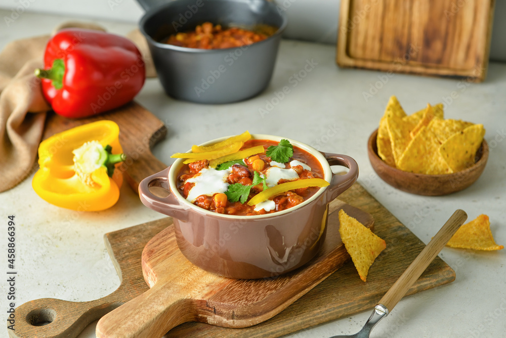Pot with delicious chili con carne and nachos on table