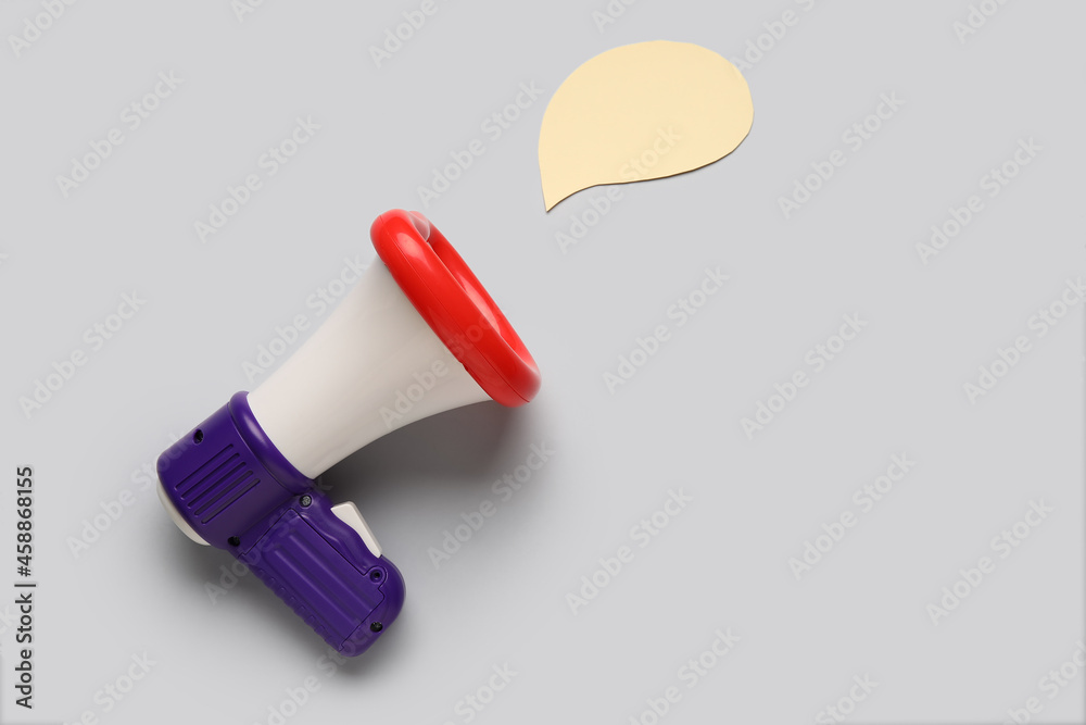 Toy megaphone and speech bubble on light background