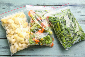 Wall Mural - Plastic bags with different frozen vegetables on color wooden background