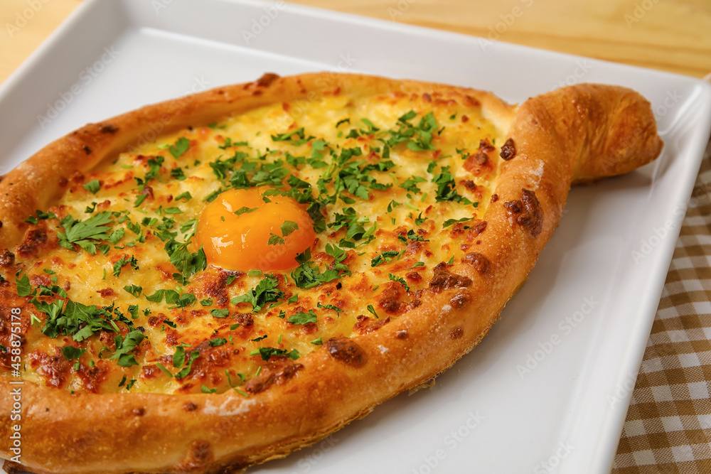 Plate with tasty Ajarian khachapuri on table, closeup