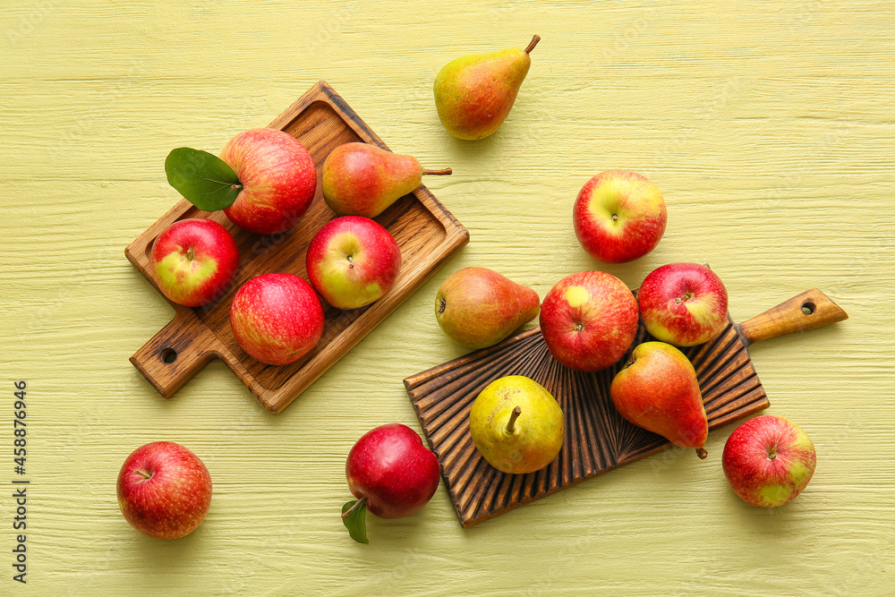 Wooden boards with ripe pears and apples on color background