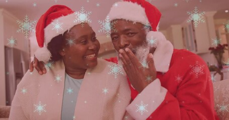 Canvas Print - Animation of snow falling over smiling couple wearing santa hats and waving hands