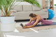© Studio Romantic - Fit young woman doing her routine sports workout at home. Beautiful slim Caucasian lady doing leg stretching exercise while practicing pilates on fitness mat on floor in modern light living room