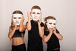 small Americans children actors with white masks of mime on their face holding it with their hands on the day of the theater depicting theatrical isra