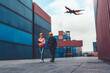 © InfiniteFlow - Industrial worker works with co-worker at overseas shipping container port . Logistics supply chain management and international goods export concept .
