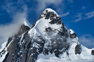 Wall Mural - Beautiful view of a snow-covered mountain under a dark blue sky with clouds