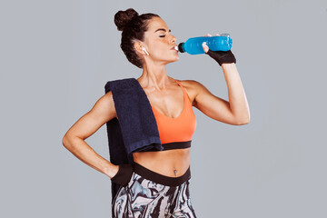 Young woman drinking isotonic drink bottle after workout