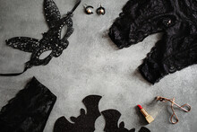 Flat Lay Composition With Black Sexy Lace Face Mask And Lingerie For Halloween Party On Grey Background, Top View From Above