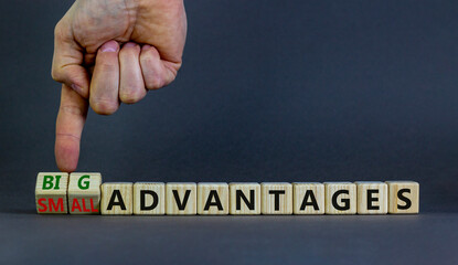 Big or small advantages symbol. Businessman turns wooden cubes, changes words Small advantages to big advantages. Beautiful grey background, copy space. Business, small or big advantages concept.