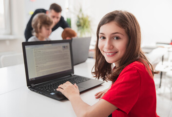 Wall Mural - happy girl working on laptop in classroom
