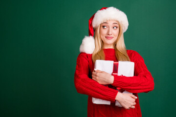 Sticker - Photo of sweet shiny young lady wear red sweater headwear smiling hugging gift looking empty space isolated green color background