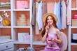 © alfa27 - happy redhead woman among many clothes in her closet with smartphone and credit bank card shopping online via internet, shopaholic enjoys shopping, consumer psychology, consumer generation