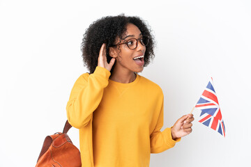 Sticker - Young African American woman holding an United Kingdom flag isolated on white background listening to something by putting hand on the ear