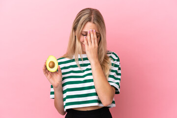 Poster - Young caucasian woman holding an avocado isolated on pink background with tired and sick expression