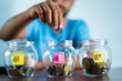 Focus on jar, Man from behind placing coins inside the jar - Concept of monthly SIP or systematic investment plan