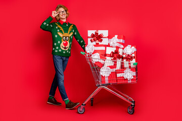 Sticker - Full length body size view of attractive cheerful guy carrying cart going eve day isolated over bright red color background