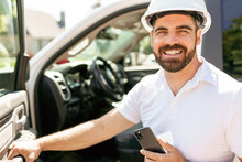 Man Engineer Builder Wearing A White Hard Hat, Shirt In Front Of His Pickup Using Cellphone