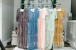 Beautiful bridesmaid dresses hanging on hangers waiting on wedding ceremony with names cards on it Gorgeous different color bridesmaids dresses hanging in the room