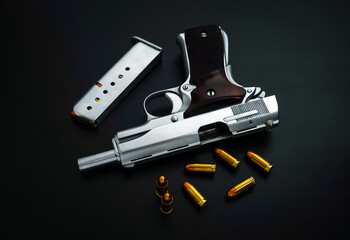 Close-Up handgun with golden sharp bullets on a black surface.                  