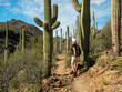 Retired woman waking in a trail among saguaro in the desert of Arizona