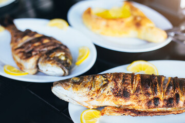 Fried fish with lemon wedges on a white plate - sea bass and dorado