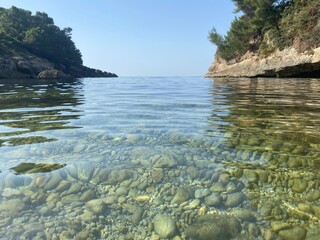 Canvas Print - Pebble beach of Mediterranean sea. Beautiful calm clear water. Rocky coast of the sea. Summer. Relax. Tranquility.