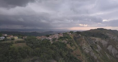 Wall Mural - A beautiful view of green mountains and residential buildings under a cloudy sky