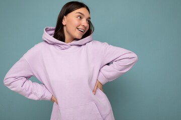 Shot of attractive happy smiling young woman wearing casual outfit standing isolated over colourful background with empty space looking to the side