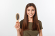 Happy young woman combing her long healthy hair on white background.