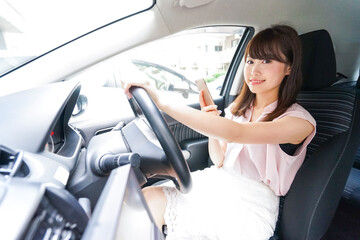 Wall Mural - スマホを使いながら運転する女性