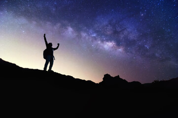 Wall Mural - Landscape with Milky Way. Night sky with stars and silhouette of a standing happy man on the mountain, Success or winner, leader concept. High iso with Noise.