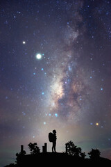 Wall Mural - landscape with milky way. night sky with stars and silhouette of a standing happy backpacker women o