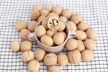 Aufkleber - A lot of whole walnuts in a cup on a napkin closeup. Healthy, organic and healthy food with a high content of protein and protein.