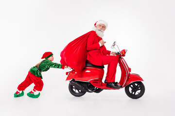 Wall Mural - Photo of team people old man ride scooter hold sack kid push wear santa elf costume isolated grey color background