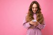 © Ivan Traimak - Beautiful smiling young woman wearing casual clothes standing isolated over background surfing on the internet via phone looking at mobile screen