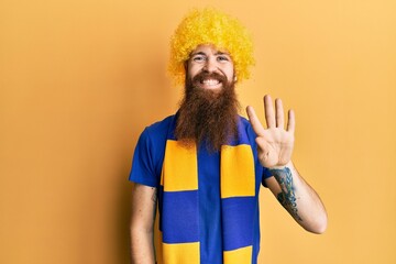 Canvas Print - Redhead man with long beard football hooligan cheering game wearing funny wig showing and pointing up with fingers number four while smiling confident and happy.