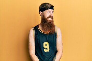 Poster - Redhead man with long beard wearing basketball uniform looking away to side with smile on face, natural expression. laughing confident.