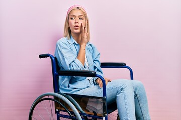 Poster - Beautiful blonde woman sitting on wheelchair hand on mouth telling secret rumor, whispering malicious talk conversation