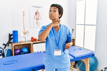 Wall Mural - Young hispanic woman with short hair working at pain recovery clinic cutting throat with hand as knife, threaten aggression with furious violence