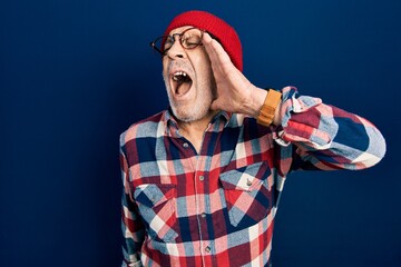 Poster - Handsome mature man wearing hipster look with wool cap shouting and screaming loud to side with hand on mouth. communication concept.