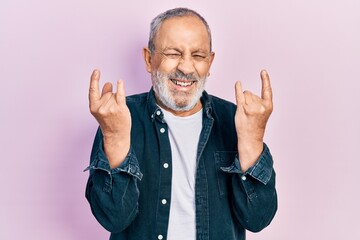 Wall Mural - Handsome senior man with beard doing rock gesture smiling and laughing hard out loud because funny crazy joke.