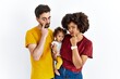 © Krakenimages.com - Interracial young family of black mother and hispanic father with daughter pointing to the eye watching you gesture, suspicious expression