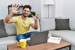 © Krakenimages.com - Young man with beard using laptop at home showing and pointing up with fingers number seven while smiling confident and happy.
