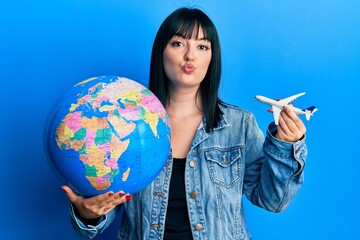 Poster - Young hispanic woman holding paper toy and world ball looking at the camera blowing a kiss being lovely and sexy. love expression.