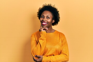 Poster - Young african american woman wearing casual clothes looking confident at the camera smiling with crossed arms and hand raised on chin. thinking positive.