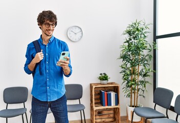 Wall Mural - Young hispanic man smiling confident using smartphone at waiting room