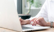 © NAMPIX - Closeup view of woman hands using laptop computer while sitting at the table in modern office room,