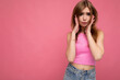 © Ivan Traimak - Young emotional sad beautiful dark blonde woman with sincere emotions isolated on background wall with copy space wearing stylish pink top looking at camera
