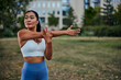 Sportswoman stretching her arms after workout in park