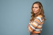 Photo portrait of young pretty beautiful angry dissatisfied blonde woman with sincere emotions wearing casual striped sweater isolated over blue background with copy space